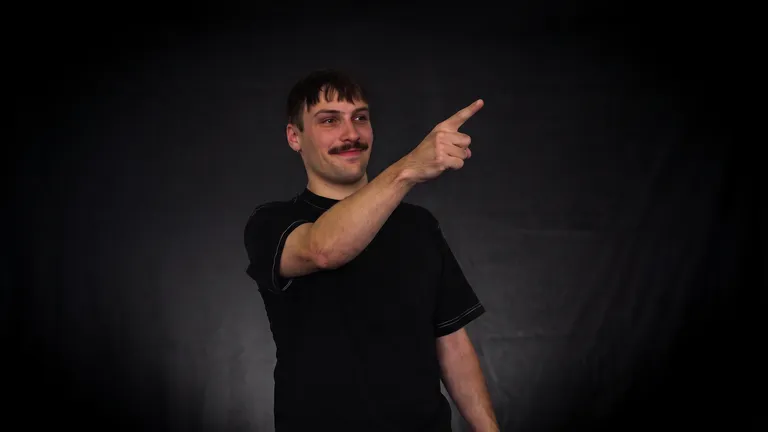 Mann zeigt mit dem Finger nach rechts und lächelt vor dunklem Hintergrund Mann mit Schnurrbart in schwarzem T-Shirt zeigt mit dem rechten Arm nach oben rechts vor schwarzem Hintergrund.